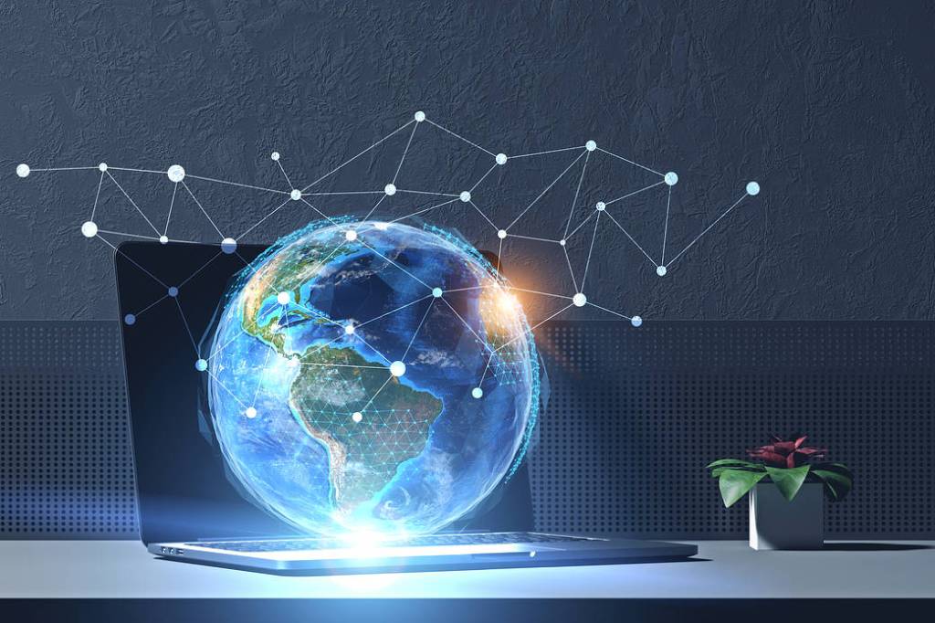 Black/grey laptop with a hologram green/blue Earth hovering over the laptop and network holograms above it.